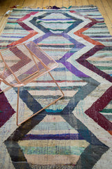 Hand woven Moroccan rag rug with geometric chevrons and multi-colored striped sections.