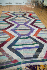 Vibrant geometric chevrons and stripes on a hand-woven Moroccan rag rug with fringe.