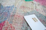 Dense, hand-woven texture of a vintage rag rug in pink, blue, and ivory.