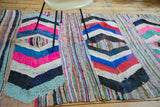 Vibrant hot pink, blue, and black chevron bands on a hand woven vintage rag rug.