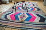 Dense hand woven Moroccan rag rug showcasing hot pink, blue diamond, and multi-color striped pattern.