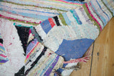 Vibrant striped textile details on a folded vintage Moroccan rag rug.
