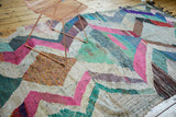 Dense handwoven texture of a vintage Moroccan rag rug with colorful zigzag motif.