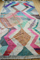 Textured weave of the vintage rag rug featuring a zigzag motif in pink, mint, and bronze.