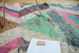 Dense woven texture of vintage Moroccan rag rug, mint, pink, ivory, blue zigzag pattern.