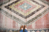 Distressed Baktiari carpet's multi-layered diamond mosaic in pale green, cinnabar, and powder blue.