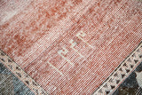 Corner of distressed Baktiari carpet with cinnabar red pile and woven inscription.