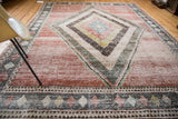 Distressed vintage Baktiari carpet corner, showing geometric tiled patterns and soft cinnabar field.