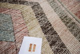 Distressed Baktiari carpet's woven mosaic pattern in muted red, blue, green, and brown.