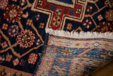 Vintage Heriz rug's hand-knotted foundation, cream fringe, and indigo blue geometric patterns.