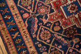 Vintage Heriz rug section highlighting intricate madder red and indigo blue geometric patterns.