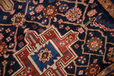 Geometric madder red medallion design, indigo field, and blush floral lattice on a vintage Heriz rug.
