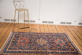 Vintage Heriz rug's triple medallion and lattice outlines in rich indigo and madder red.