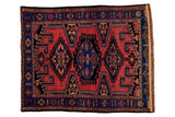 Vintage Persian rug with central hexagonal medallion, geometric patterns in brick red and indigo blue.