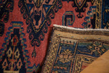 Hand-knotted vintage Persian rug folded, showing brick red field, indigo geometric pattern, and backweave.