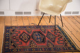 Vintage Persian rug with brick red field, indigo elongated diamond geometric patterns.
