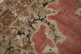Detail of the distressed antique Tabriz rug, showing intricate navy blue vines and faded floral patterns.