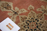 Distressed antique Tabriz rug pile, with pale rust salmon field and intricate ivory and navy floral patterns.
