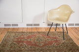 Distressed antique Persian Tabriz rug with a pale rust salmon starburst medallion and intricate floral vines.