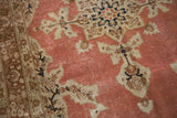 Distressed antique Tabriz rug corner with faded rust salmon, ivory, and navy floral vines.