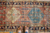 Distressed antique Persian Heriz runner with upbeat medallions, saffron, sky blue, and red tones.