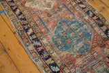 Distressed antique Heriz rug: sky blue medallion, floral fills, madder red field, and stylized trees.