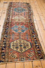 Distressed antique Persian Heriz rug detail: geometric medallion in saffron, blue, red tones.