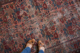 Close-up of antique Lilihan rug's distressed pile, showing jewel rose and sapphire blue florals.