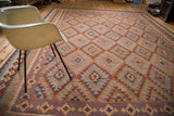 Lattice oriented serrated diamond motif on a New Kilim rug with rust, cinnabar, and blue.