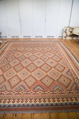 Hand-woven Kilim border with rust, ivory, and red geometric patterns, finished with tassels.