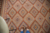 Geometric serrated diamond motif on New Kilim carpet in rust, red, and ivory hues.