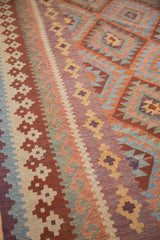 Geometric serrated diamond motifs in rust, madder red, ivory, and blue on this New Kilim carpet.