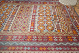Tribal Kilim carpet section showcasing fluid water channel patterns in orange, blue, and red.