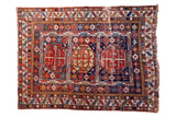 Distressed antique Shirvan rug showcasing vibrant geometric medallions in red, indigo, and ivory.