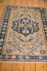 Hand-knotted Heriz rug featuring navy blue medallion, geometric motifs, and floral border.