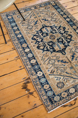 Vintage Heriz rug's lower corner, showing a navy blue border with sky blue and sand floral motifs.