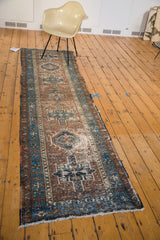 Distressed Karaja runner rug with repeating geometric medallions in brown, indigo, and ivory.