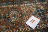 Distressed geometric medallion pattern in indigo blue, brown, and blush rose tones.