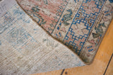 Distressed Sivas rug with muted dusty rose and blue pile, revealing hand-knotted foundation.