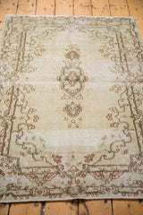 Rococo-style embellishments and distressed texture in antique ivory and light brown on the Kerman.