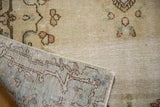 Distressed Kerman rug pile with antique ivory tones, revealing hand-knotted foundation and soft rococo motifs.
