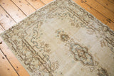 Distressed Kerman rug close-up: rococo medallion and ivory field with muted blue accents.