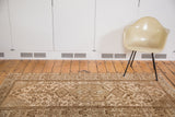 Distressed Malayer style rug detail with central medallion, warm gold, peach, and bronze brown textures.