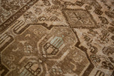 Distressed Malayer rug showing warm brown geometric motifs with subtle green accents.