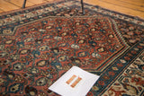 Detailed view of hand knotted Malayer rug's repeating brick red and sky blue boteh motifs.