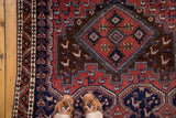 Geometric dragon border and field patterns in brick red, navy, and coffee brown.