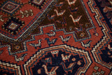 Hand-knotted vintage Afshar rug close-up: brick red field with stylized bird and geometric motifs.