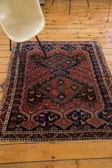 Close-up of a vintage Afshar rug's geometric border with stylized motifs in brick red and navy.