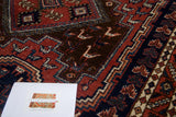 Vintage Persian Afshar rug detail with geometric dragon motifs in brick red, navy, and coffee brown.