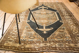 Serrated leaf border of a vintage Persian Sarab rug with a dark blue-black field.